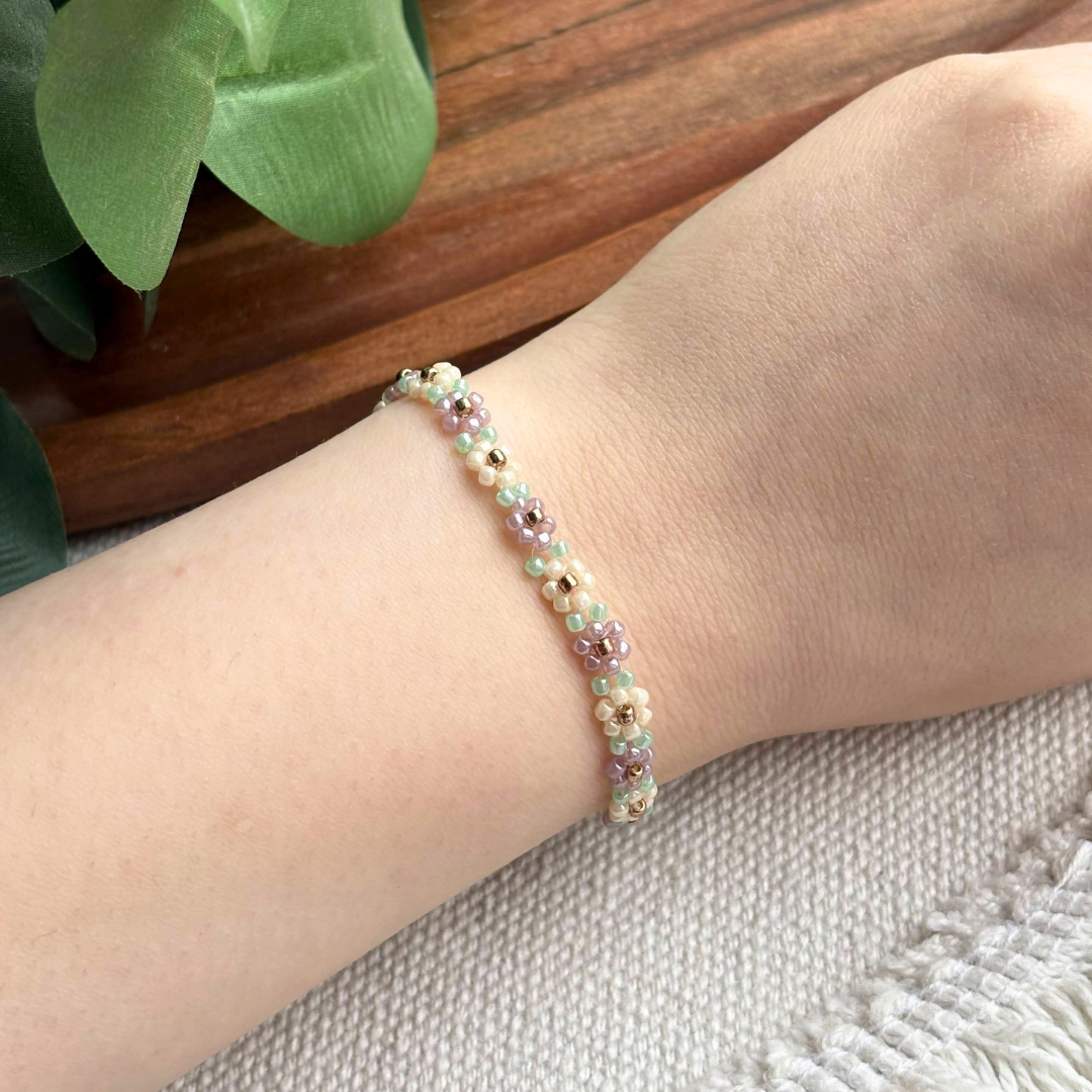 Bratara eleganta cu margele pastel si flori mini, lucrata manual, cu accente aurii. Martisor modern si feminin, ideal pentru cadou de primavara si pentru a completa orice outfit.