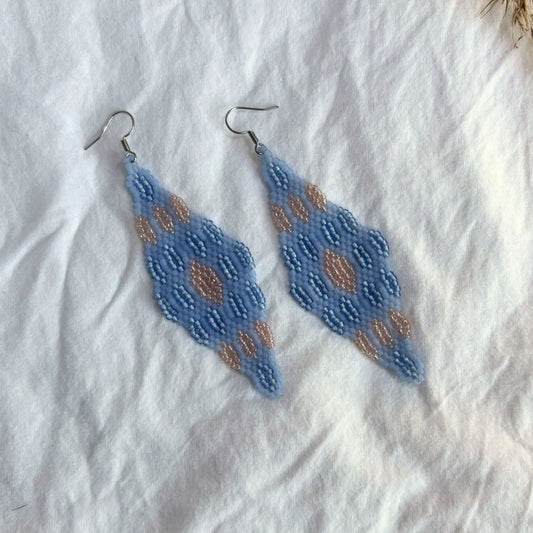 Cercei handmade lungi din mărgele fine în nuanțe de albastru deschis cu accente bej-aurii, design geometric tip romb, cercei statement ușori, stil boho și elegant, bijuterii artizanale unicat potrivite pentru ținute de zi sau evenimente speciale.