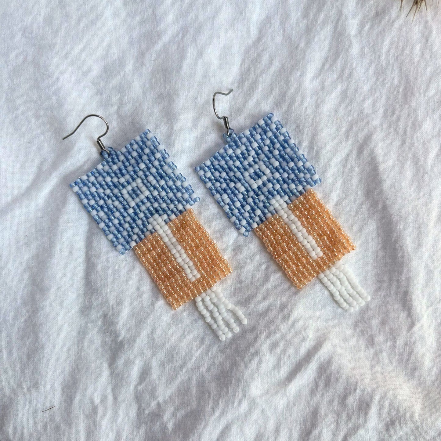 Cercei lungi statement lucrați manual din mărgele fine, model geometric, în nunțe pastel de albasru și portocaliu si alb, accesorii artizanale unicat, modele originale, ideali de cadou pentru femei, stil boho modern, casual și de ocazie.