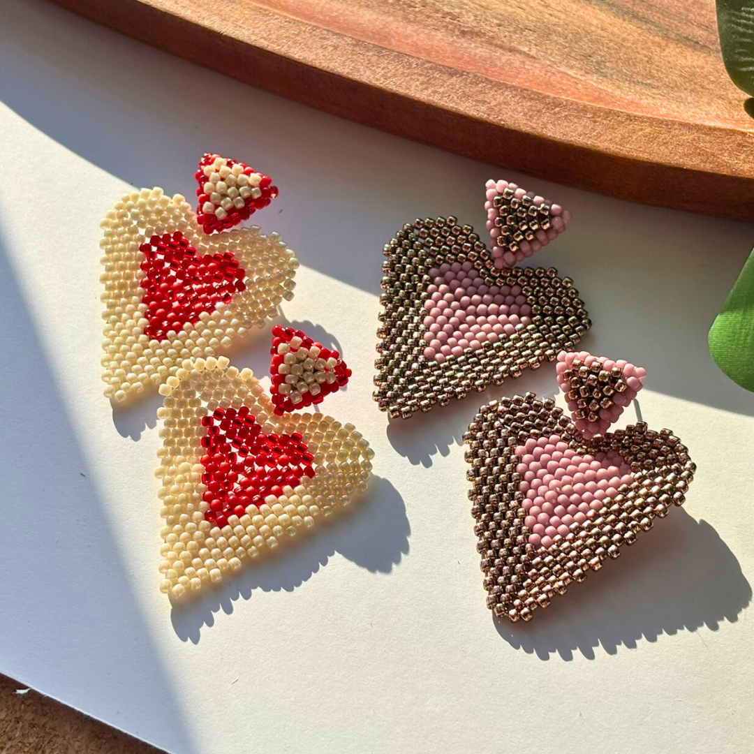 Cercei statement handmade în formă de inimă, lucrați manual din mărgele crem cu roșu și roz cu bronz, design romantic și modern – bijuterii ideale pentru cadou, Valentine’s Day sau ocazii speciale.