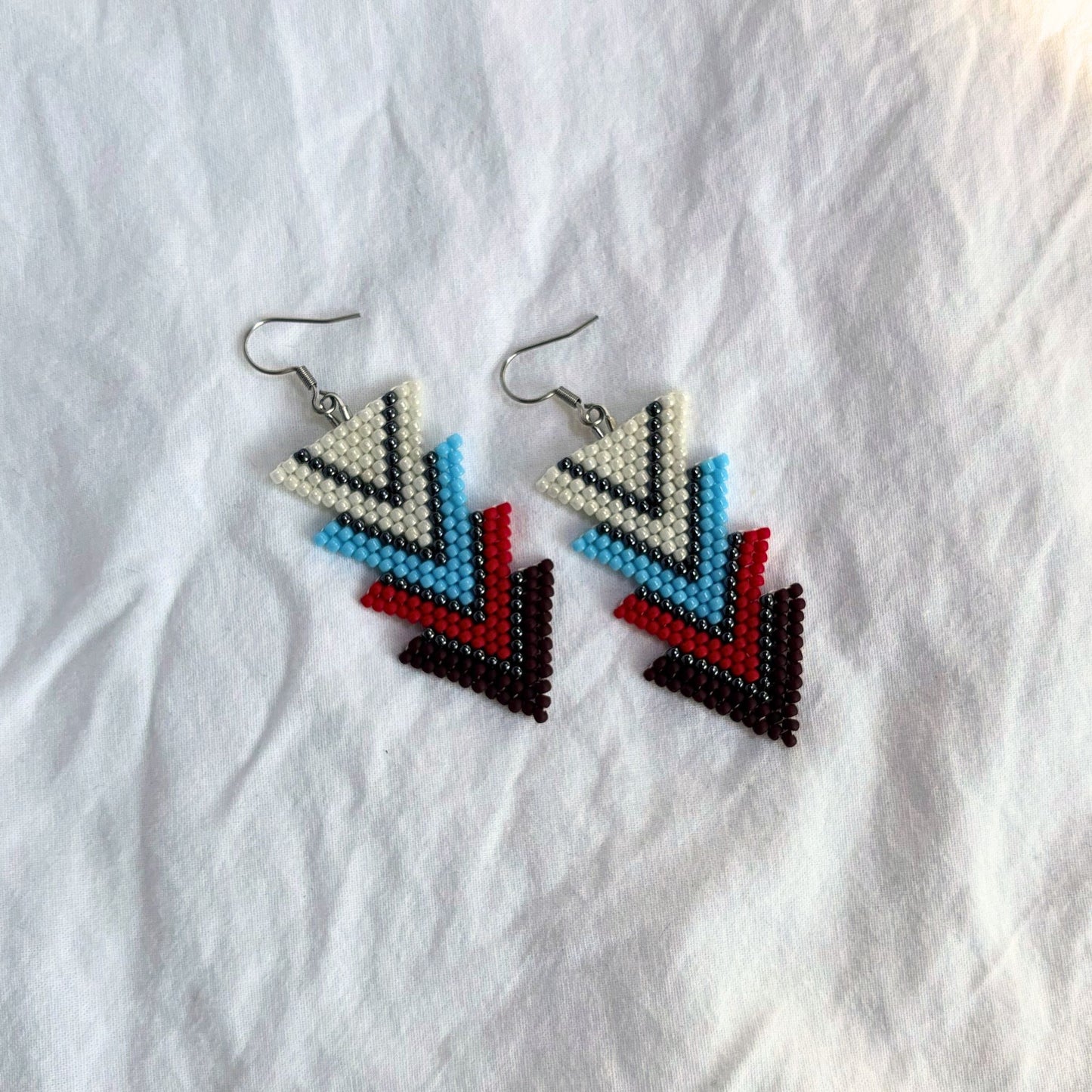 Cercei handmade din mărgele fine, model geometric triunghiular, în culori de alb perlat, albastru, roșu, grena, cercei statement ușori, bijuterii artizanale unicat, stil boho-modern, original, ideali pentru ținute casual sau de ocazie sau pentru cadou.