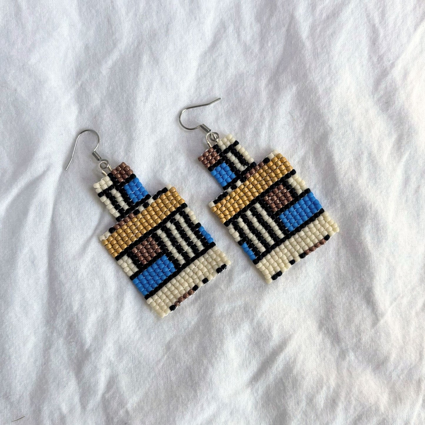 Cercei handmade din mărgele fine, model geometric dreptunghiular cu influențe etnice, combinație de albastru, crem, maro și auriu, cercei statement ușori, bijuterii artizanale unicat, stil boho modern, ideali pentru ținute casual sau elegante.