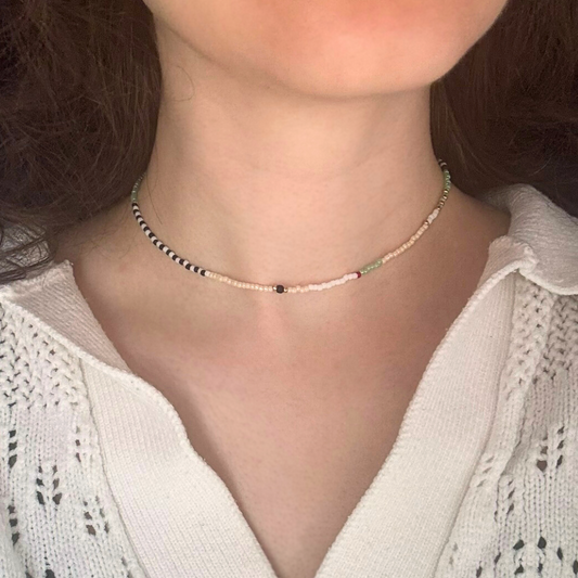 Colier choker handmade lucrat manual din mărgele fine în nuanțe neutre și accente discrete (alb, negru, verde mentă), purtat la gât – bijuterie minimalistă, ușoară, ideală pentru ținute casual sau cadou.