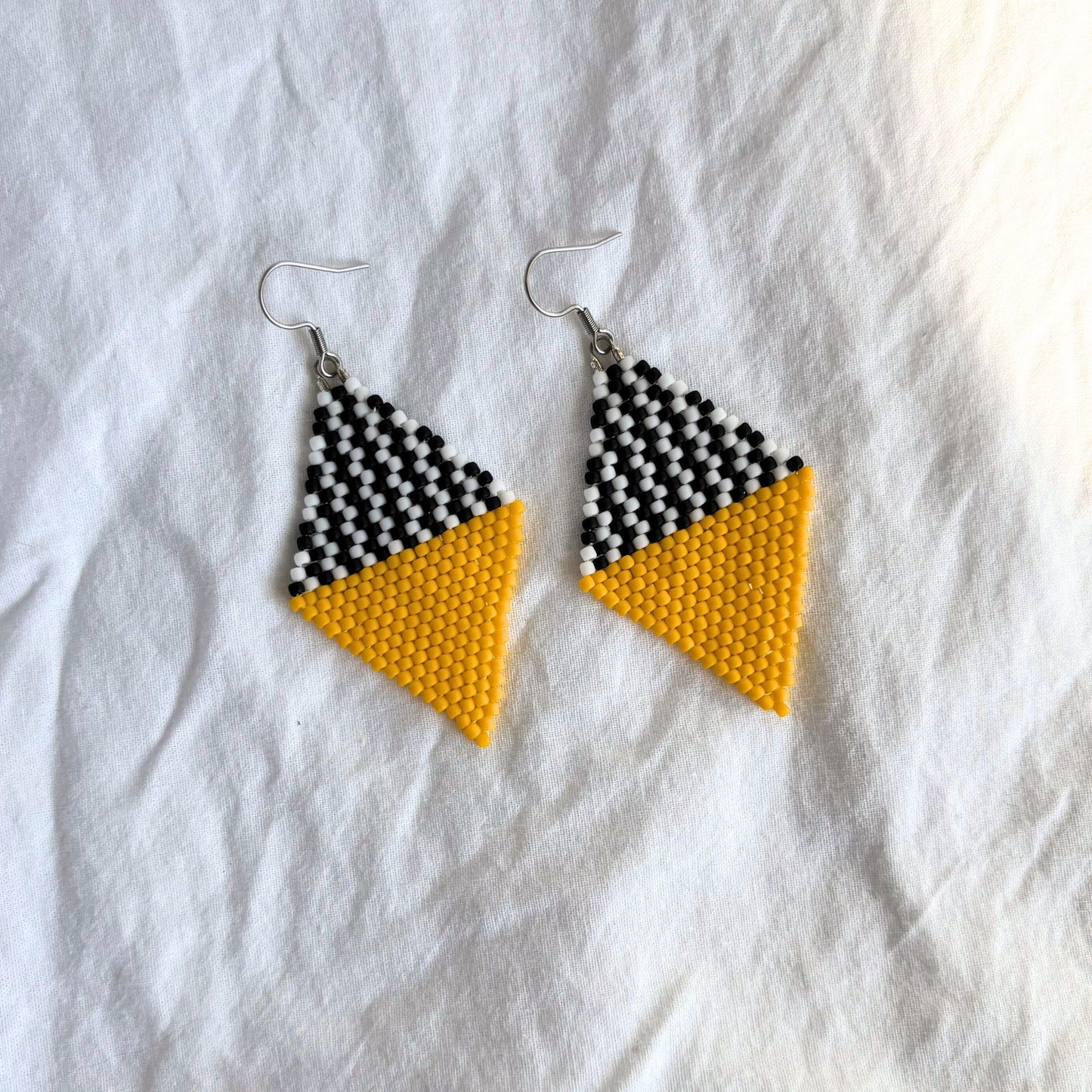 Cercei handmade din margele delicate, in combinatie de galben cu alb si negru, cercei statement usori, bijuterii artizanale unicat, stil modern contemporan, design geometric tip romb, potriviti pentru cadou, in tinute casual de zi sau pentru ocazii si evenimente speciale.