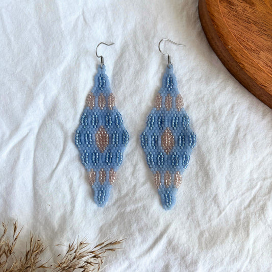 Cercei handmade lungi realizați din mărgele fine în nuanțe de albastru pastel și accente roz, design geometric simetric tip romb, cercei statement ușori, stil boho-elegant, bijuterii artizanale unicat potrivite pentru ținute de zi, vară și evenimente speciale.