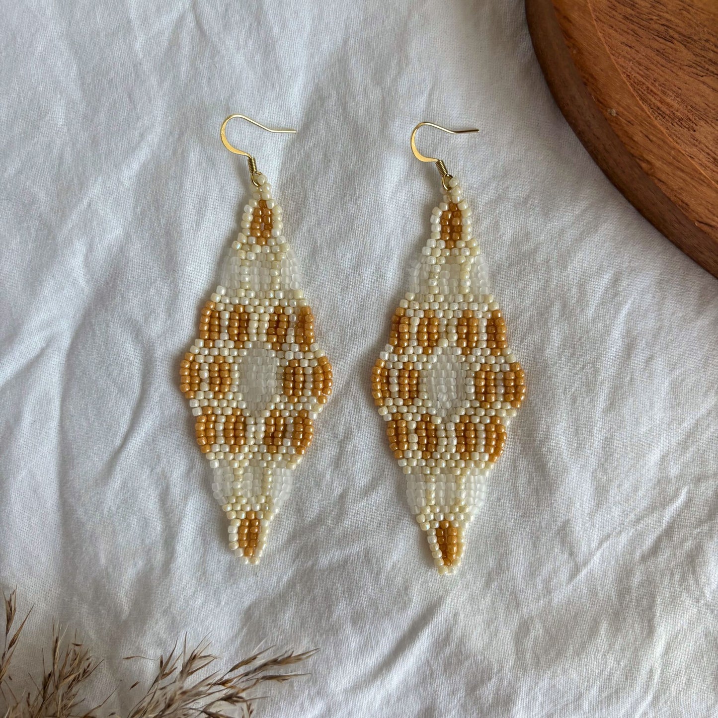 Cercei handmade lungi din mărgele mici, cu design geometric elegant în nuanțe de bej, ivoire și caramel, cercei ușori stil boho, realizați manual, accesorii statement pentru ținute casual, de vară sau ocazii speciale, bijuterii artizanale unicat.