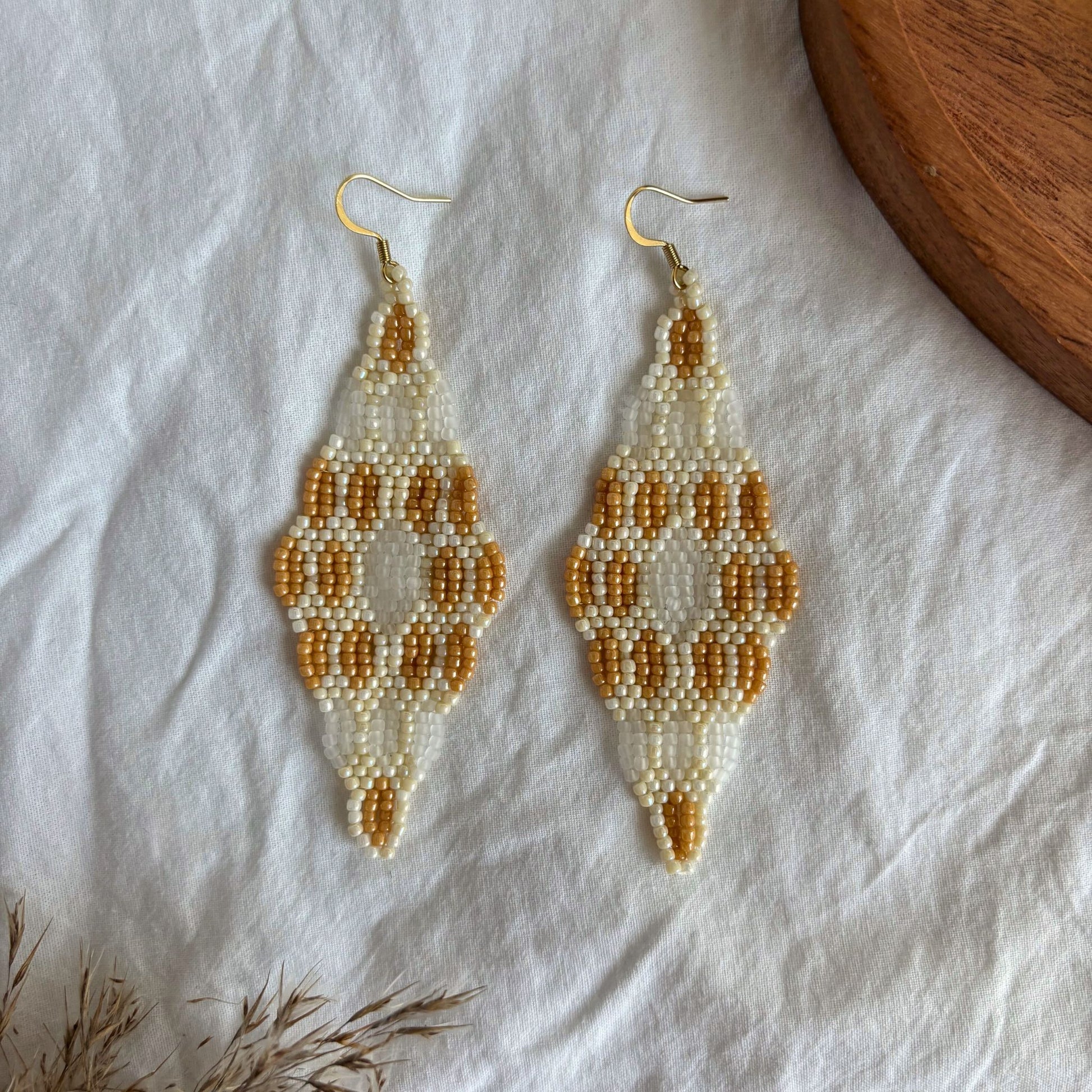Cercei handmade lungi din mărgele mici, cu design geometric elegant în nuanțe de bej, ivoire și caramel, cercei ușori stil boho, realizați manual, accesorii statement pentru ținute casual, de vară sau ocazii speciale, bijuterii artizanale unicat.