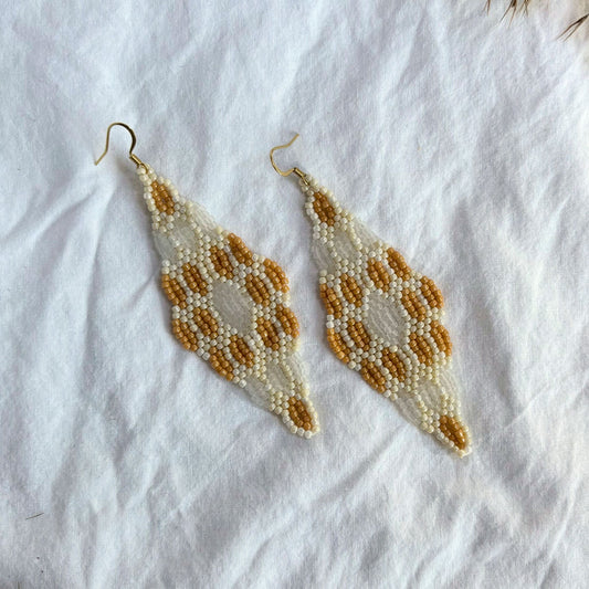 Cercei handmade lungi realizați din mărgele fine, cu design geometric simetric în culori caramel, bej și ivoire, cercei statement ușori, stil boho-elegant, bijuterii artizanale unicat potrivite pentru ținute de vară, evenimente speciale sau cadou.