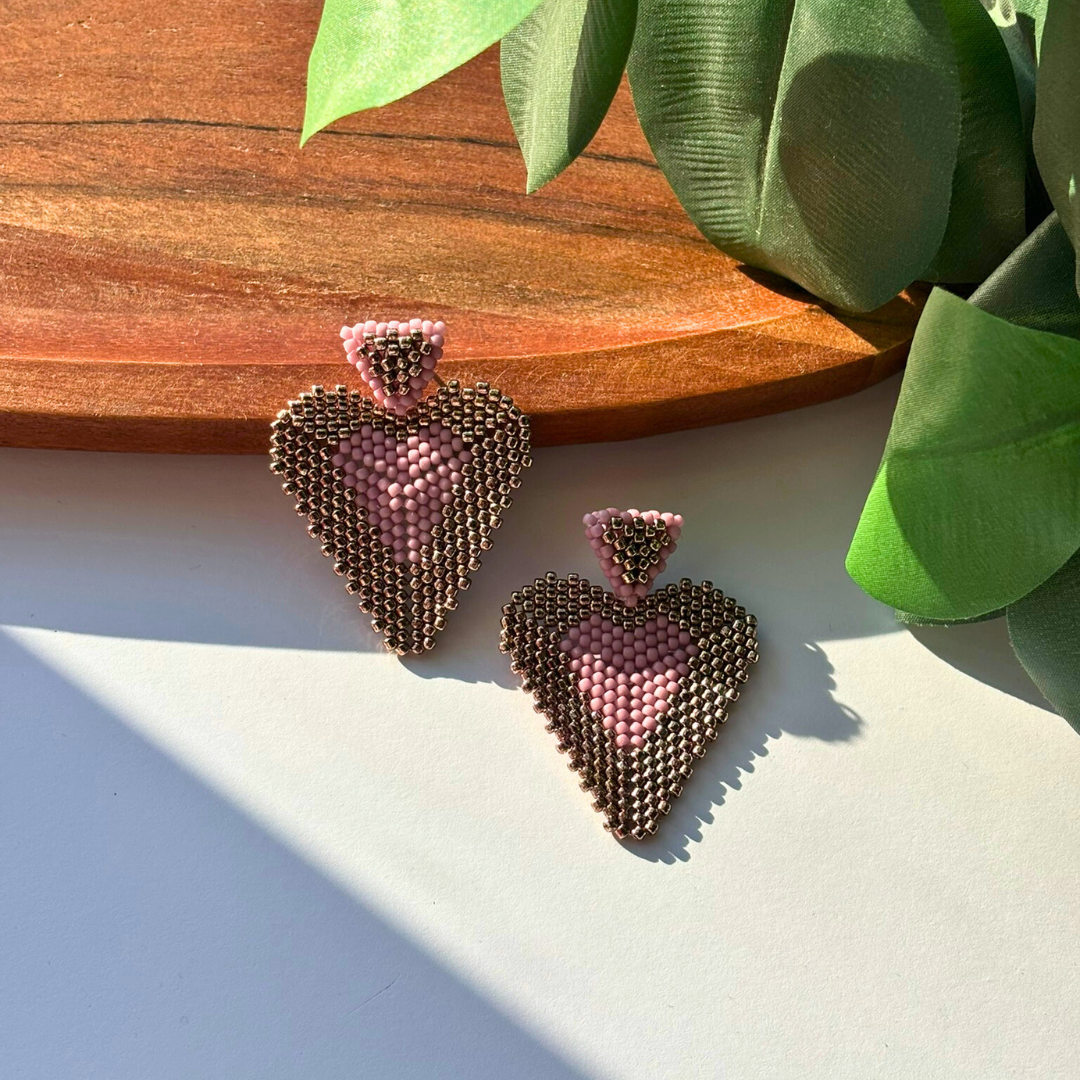 Cercei statement handmade în formă de inimă, realizați din mărgele roz prăfuit și bronz, cu design elegant și modern – bijuterii lucrate manual, ideale pentru cadou sau ocazii speciale.