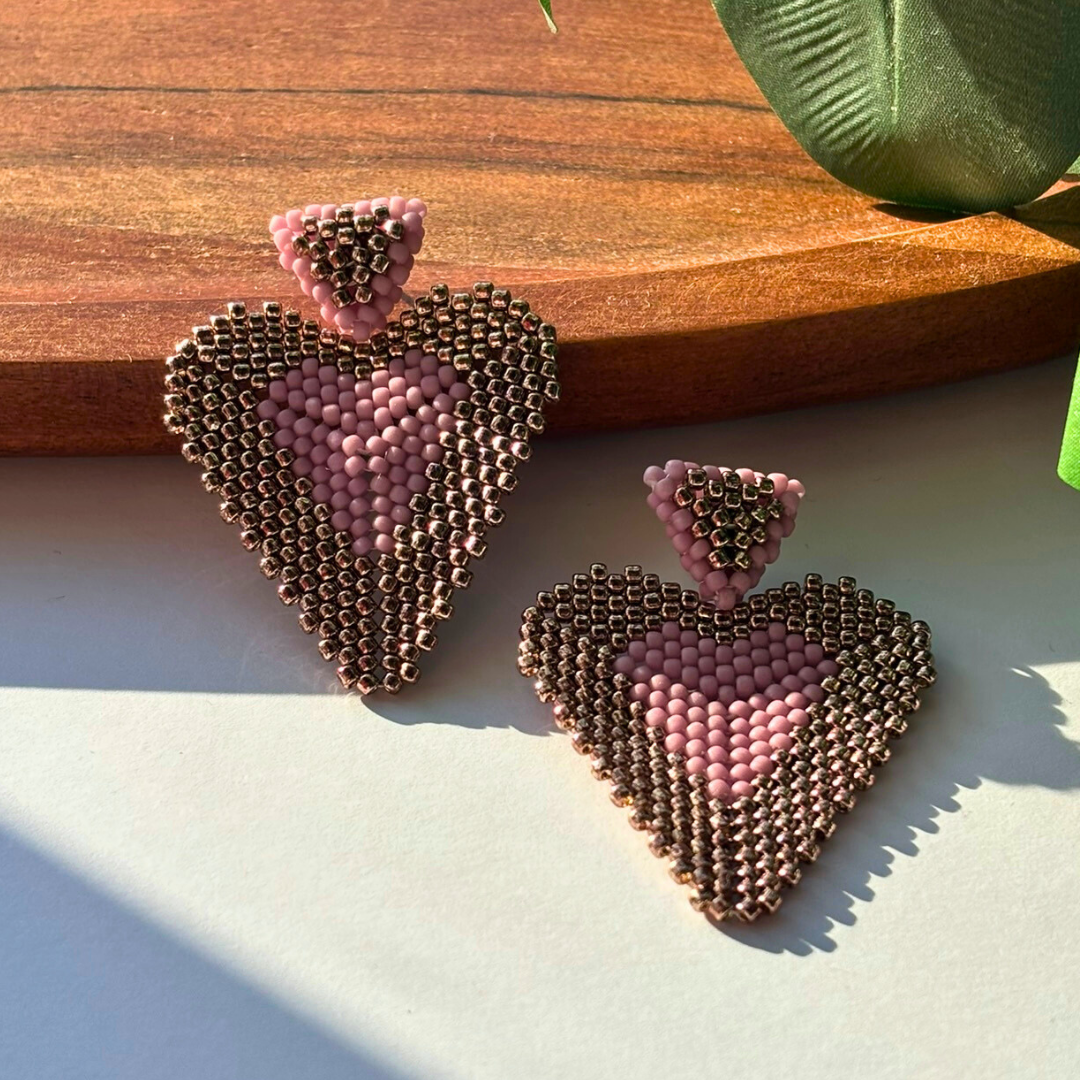 Cercei statement handmade, lucrați manual, în formă de inimă, din mărgele roz prăfuit și bronz, design elegant și modern – bijuterii feminine ideale pentru cadou sau ocazii speciale.