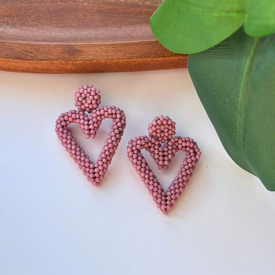 Cercei handmade în formă de inimă, realizați din mărgele roz prăfuit, cu design delicat și feminin – accesorii romantice ideale pentru cadou sau ocazii speciale.