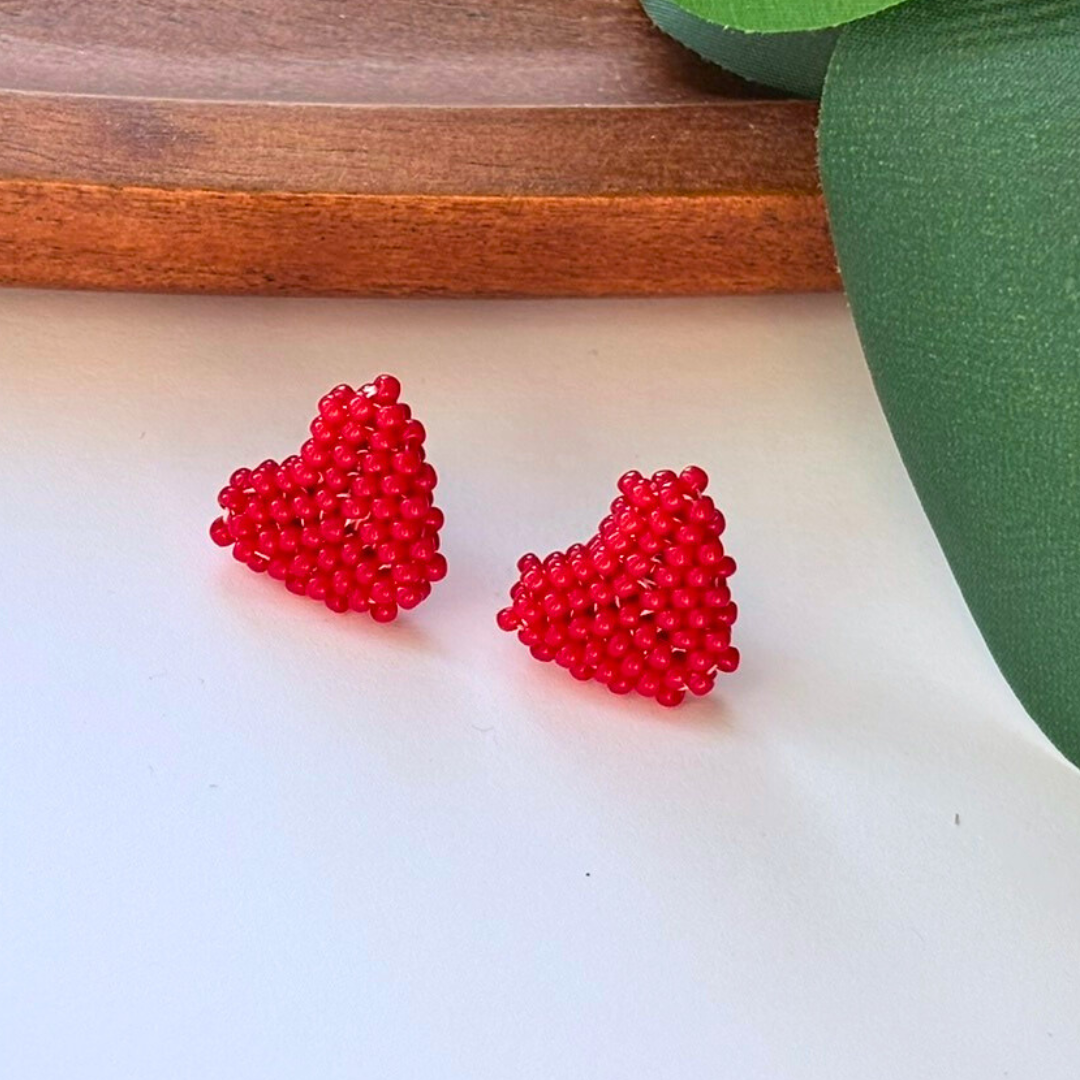 Cercei handmade tip tinta în formă de inimă, realizați din mărgele roșii, fotografiați pe fundal natural – bijuterii romantice, minimaliste, ideale pentru cadou de Valentine’s Day.