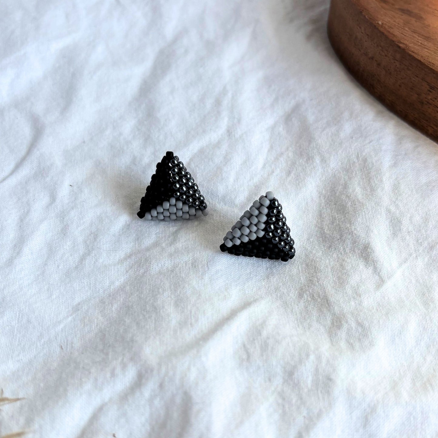 Cercei stud triunghiulari handmade din mărgele, combinație elegantă de negru, gri și accente lucioase, design geometric modern, bijuterii artizanale minimaliste pentru femei, potrivite pentru ținute casual sau elegante.