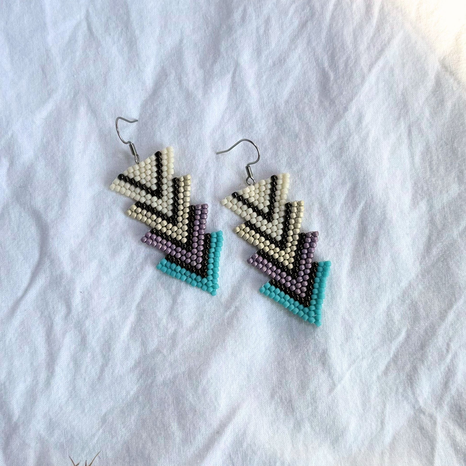 Cercei handmade lungi, model geometric triunghiular, combinație de alb perlat, bej, mov și turcoaz, bijuterii artizanale originale, accesorii moderne pentru femei și fete, ideali pentru cadou, ținute casual sau elegante.