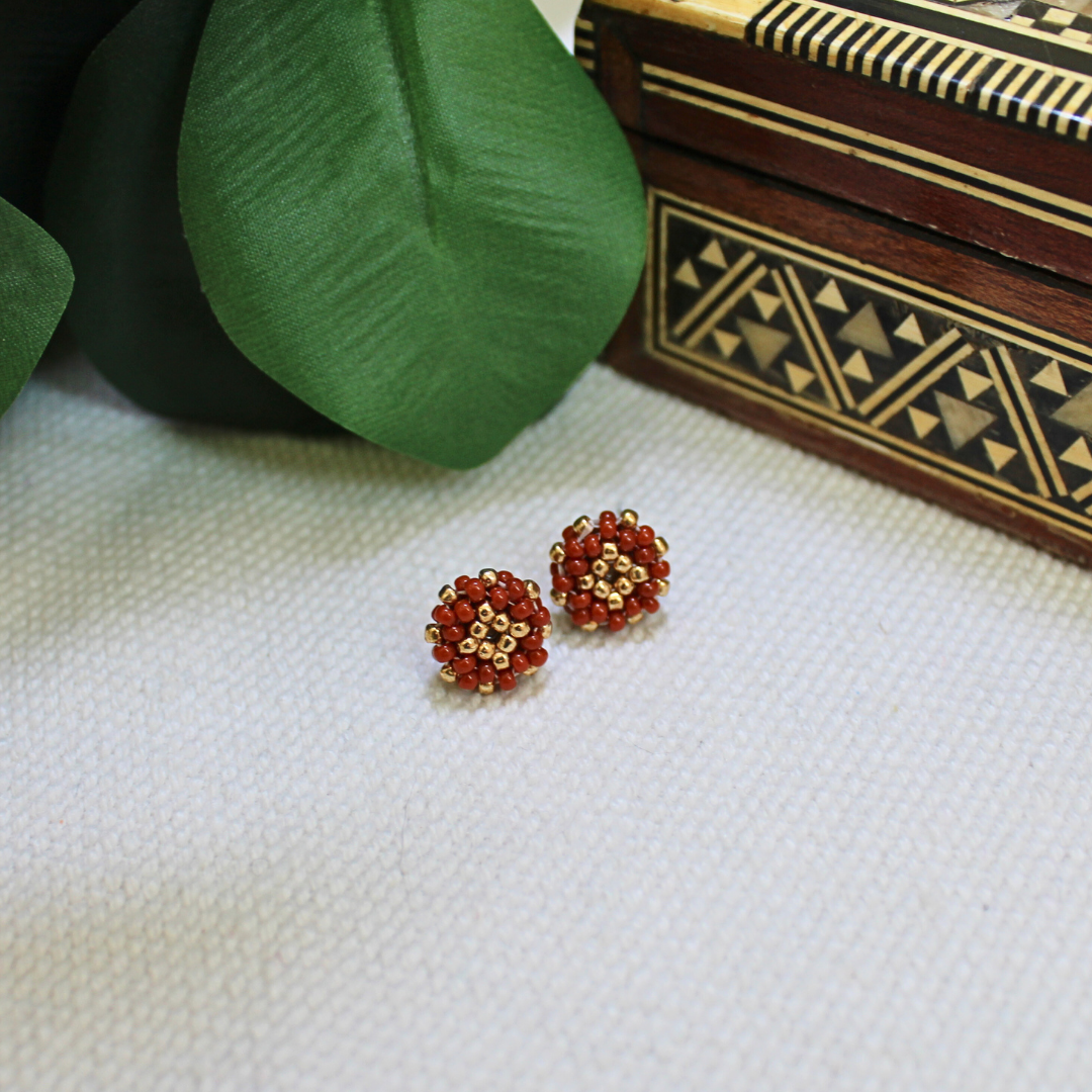 Cercei mici stud handmade din mărgele roșii cu accente aurii, design rotund elegant, bijuterii artizanale realizate manual, accesorii discrete și rafinate, ideale pentru purtare zilnică, ținute elegante sau cadou special.
