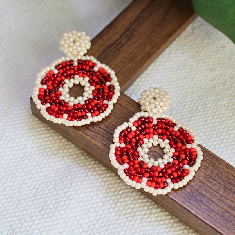 Cercei rotunzi handmade din mărgele roșii și albe, cu design geometric și cerc decupat, accesorii artizanale realizate manual, bijuterii feminine statement potrivite pentru ținute elegante, evenimente speciale sau cadou original.
