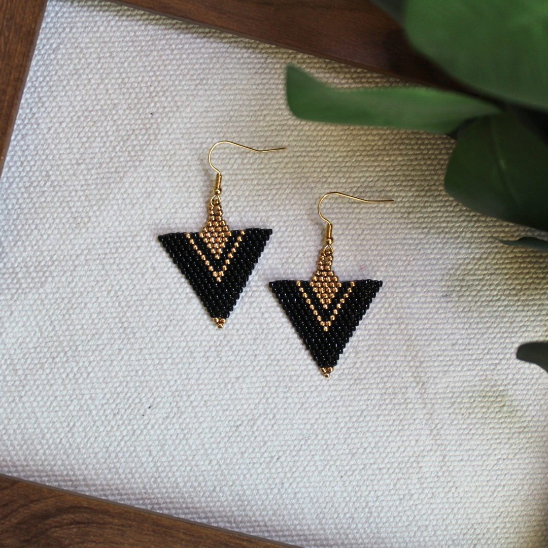 Cercei triunghiulari handmade din mărgele negre și aurii, cu design geometric elegant, agățătoare aurie, bijuterii artizanale realizate manual, potrivite pentru ținute moderne, elegante sau boho chic.