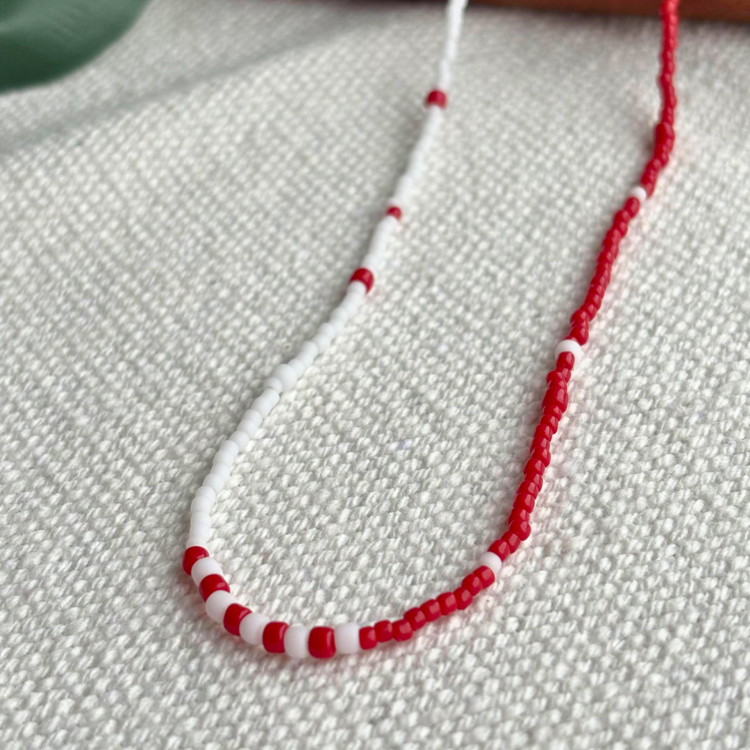 Colier Martisor handmade rosu-alb din margele mici, design discret si elegant. Ideal pentru cadou de 1 Martie, pentru colege, prietene sau mama, livrat gata de daruit.