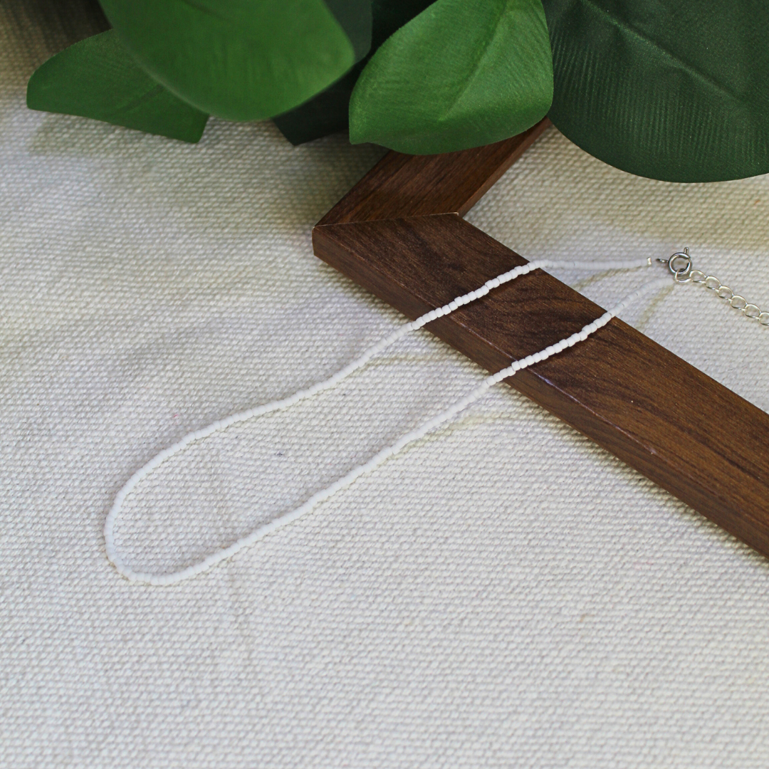Colier choker, la baza gatului, handmade lucrat manual din mărgele fine albe, design minimalist și delicat, așezat pe suport din lemn – bijuterie ușoară, elegantă, ideală pentru purtare zilnică, layering sau cadou.