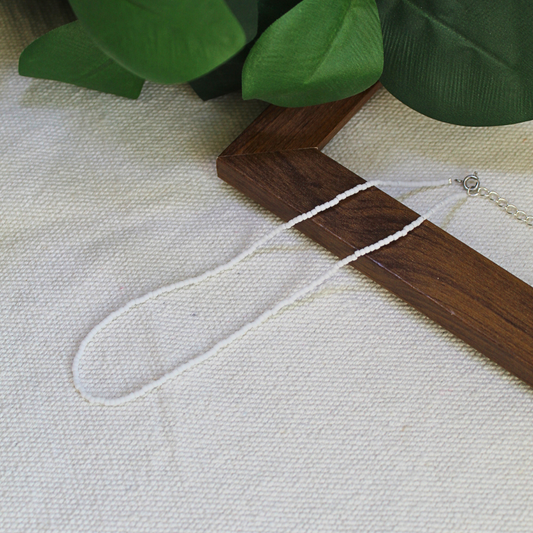 Colier choker, la baza gatului, handmade lucrat manual din mărgele fine albe, design minimalist și delicat, așezat pe suport din lemn – bijuterie ușoară, elegantă, ideală pentru purtare zilnică, layering sau cadou.