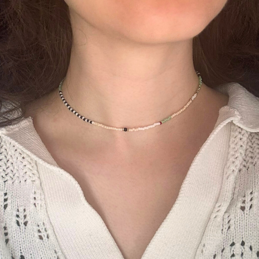 Colier choker handmade lucrat manual din mărgele fine în nuanțe neutre și accente discrete (alb, negru, verde mentă), purtat la gât – bijuterie minimalistă, ușoară, ideală pentru ținute casual sau cadou.