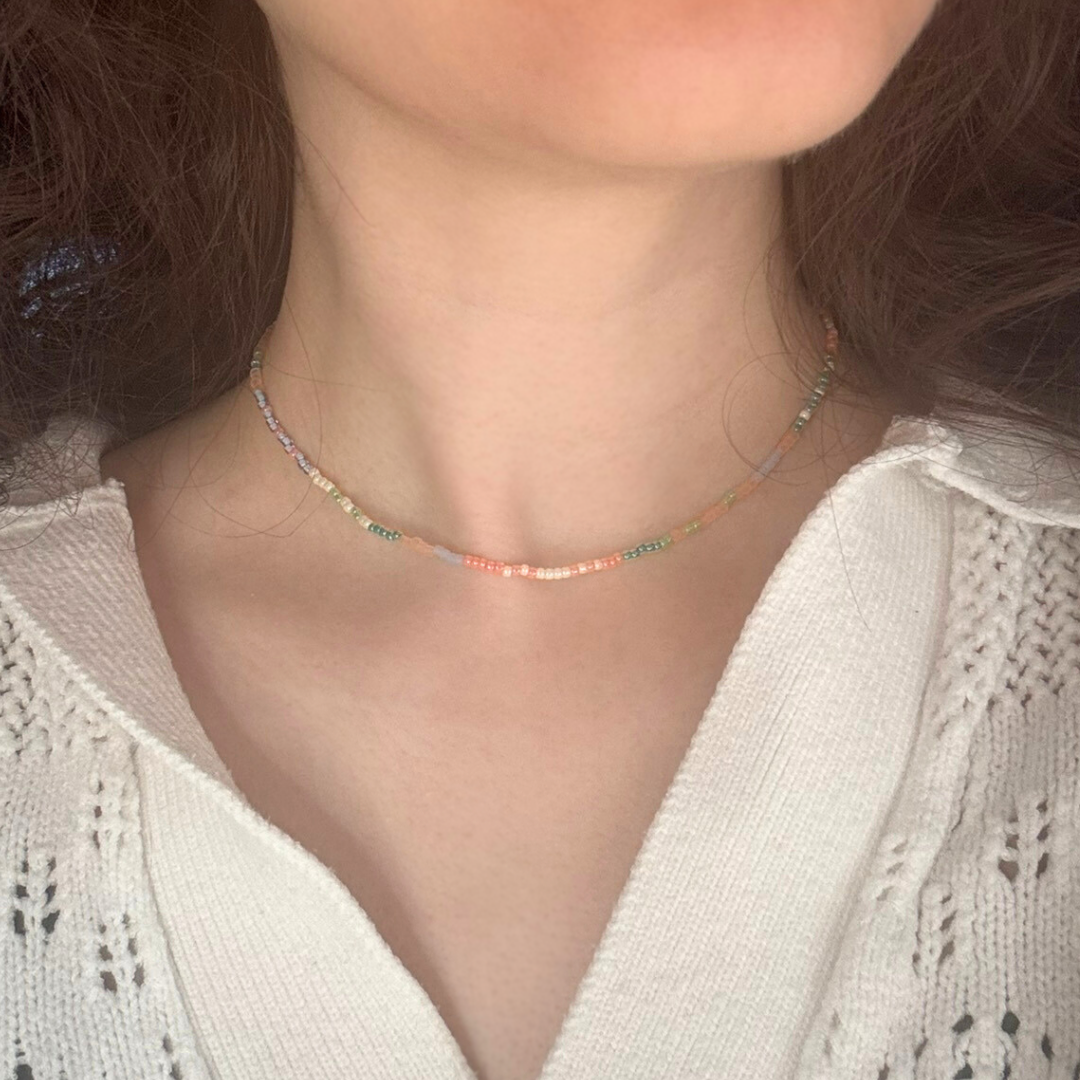 Colier la baza gatului handmade lucrat manual din mărgele fine în nuanțe pastel (roz, verde, albastru și crem), purtat la gât, design minimalist și delicat – bijuterie ușoară, perfectă pentru ținute casual sau cadou special.