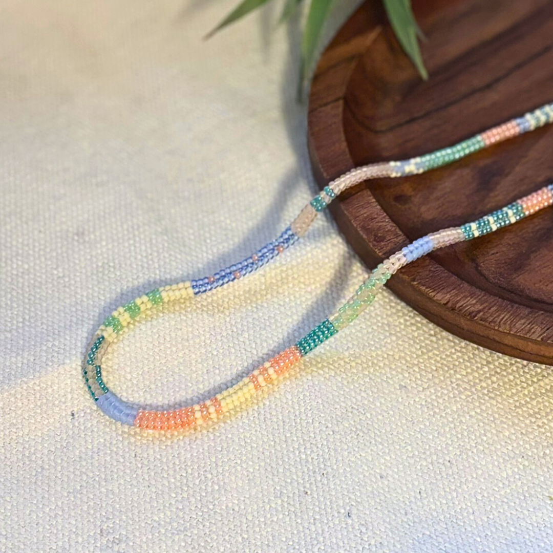 Colier handmade lucrat manual din mărgele fine în nuanțe pastel (albastru, verde, roz și crem), design delicat și minimalist – bijuterie ușoară, ideală pentru purtare zilnică sau cadou.