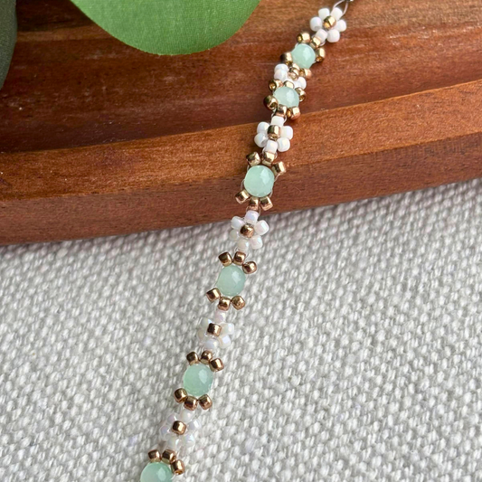 Martisor bratara handmade din margele albe perlate si detalii aurii, cu pietre verde menta. Cadou feminin, usor de purtat, perfect pentru 1-8 martie.