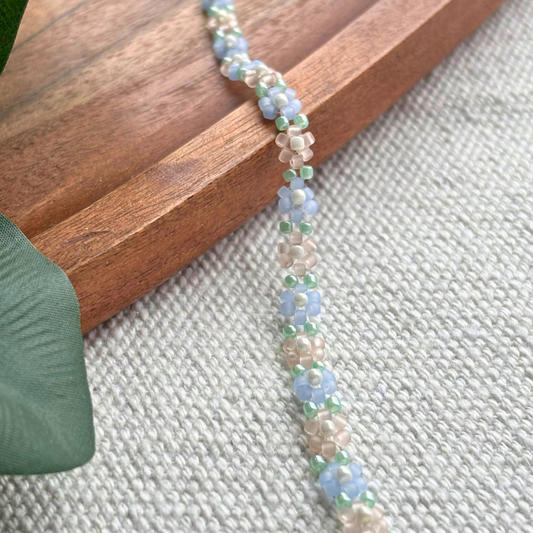 Martisor bratara lucrata manual din margele, cu flori bleu si tonuri nude, accente verzi. Ideala pentru un cadou de primavara, feminina si usoara.