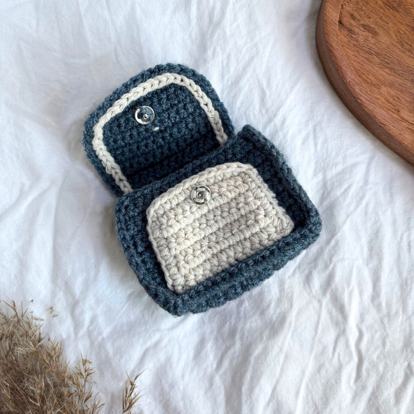 Portofel croșetat handmade în nuanțe de albastru și crem, realizat manual din fir textil, cu închidere cu capsă metalică, ideal pentru monede, carduri sau obiecte mici, accesoriu minimalist și cadou artizanal.