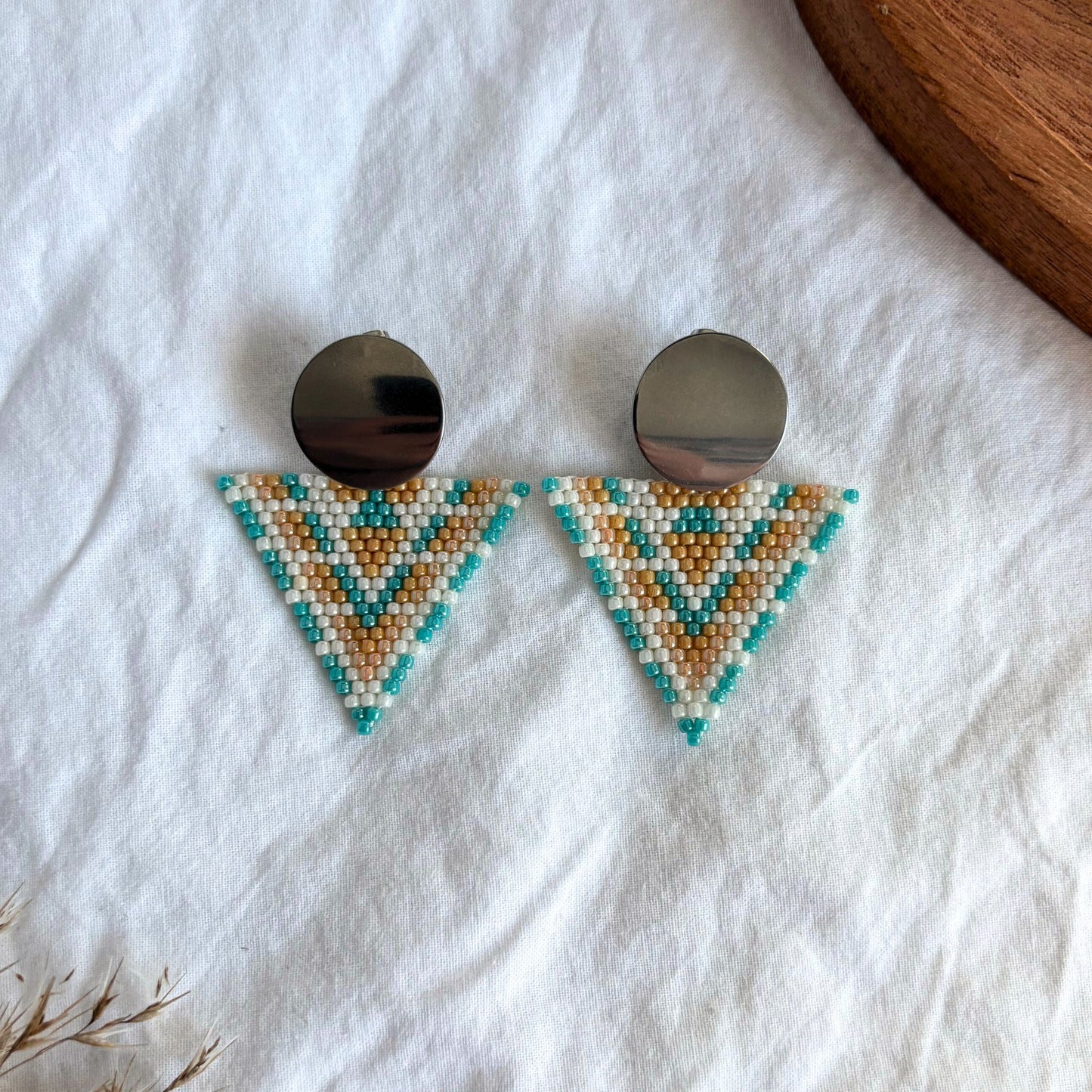 cercei lucrati manual din margele delicate, model geometric statement tip triunghi cu accesoriu rotund metalic, in nuante pastel de turcoaz, portocaliu si alb perlat, cercei statement usori, bijuterii artizanale unicat, ideali pentru cadou, tinute de zi si evenimente speciale.