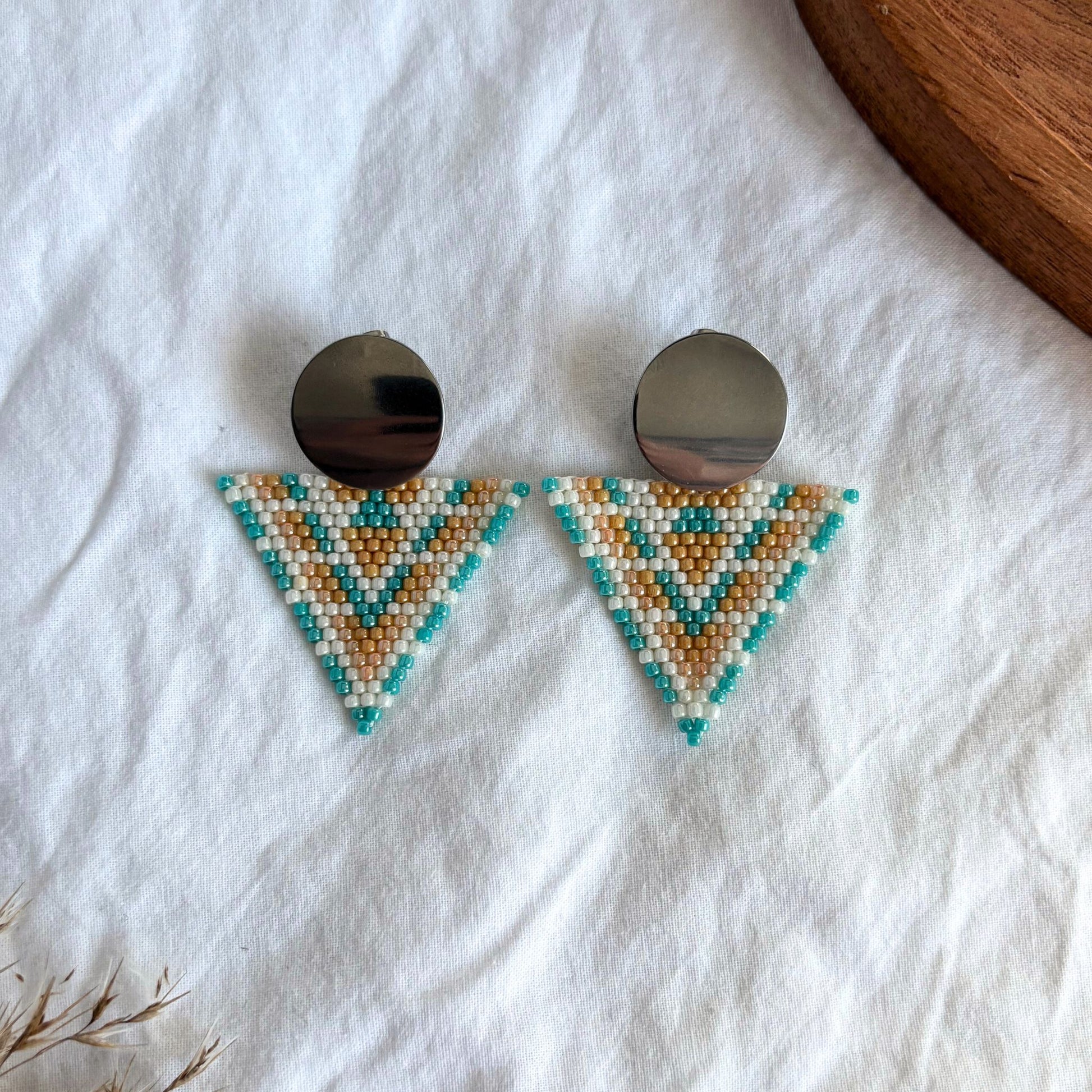 cercei lucrati manual din margele delicate, model geometric statement tip triunghi cu accesoriu rotund metalic, in nuante pastel de turcoaz, portocaliu si alb perlat, cercei statement usori, bijuterii artizanale unicat, ideali pentru cadou, tinute de zi si evenimente speciale.